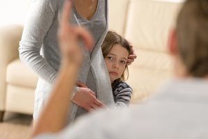 Scared little girl hiding behind her mother