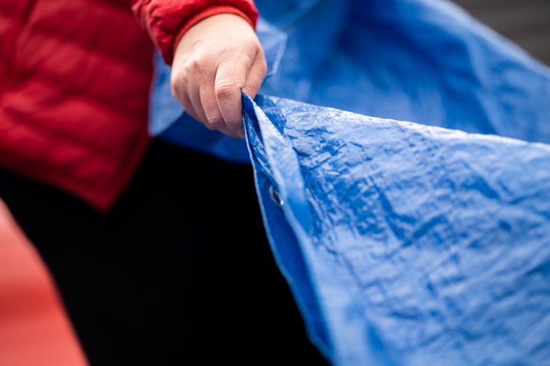 folding up a blue tarp after camping at a music festival