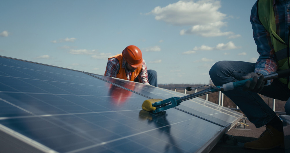 2 workers cleaning and maintaining solar panels