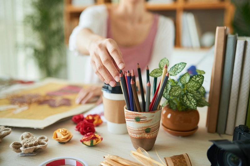 Creative woman taking colored pencil from holder while sitting