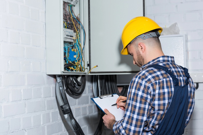 Professional electrician inspecting wires in electrical box Professional electrician inspecting wires in electrical box