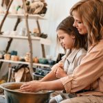 Sitting together. Mother with little girl doing pottery at home.