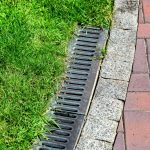 Iron gutter with grate to the drainage system on the side of the pavement