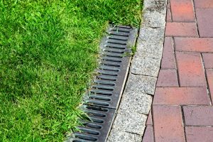 Iron gutter with grate to the drainage system on the side of the pavement