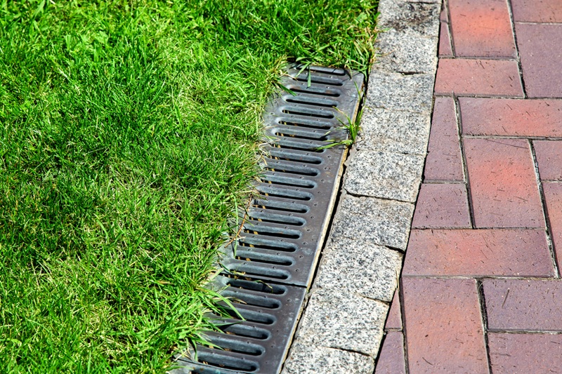 Iron gutter with grate to the drainage system on the side of the pavement