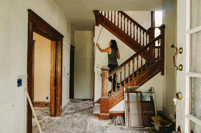A Woman in Gray Tank Top Standing on Wooden Staircase