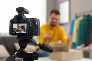 Fashion blogger with parcels recording video at home, focus on camera
