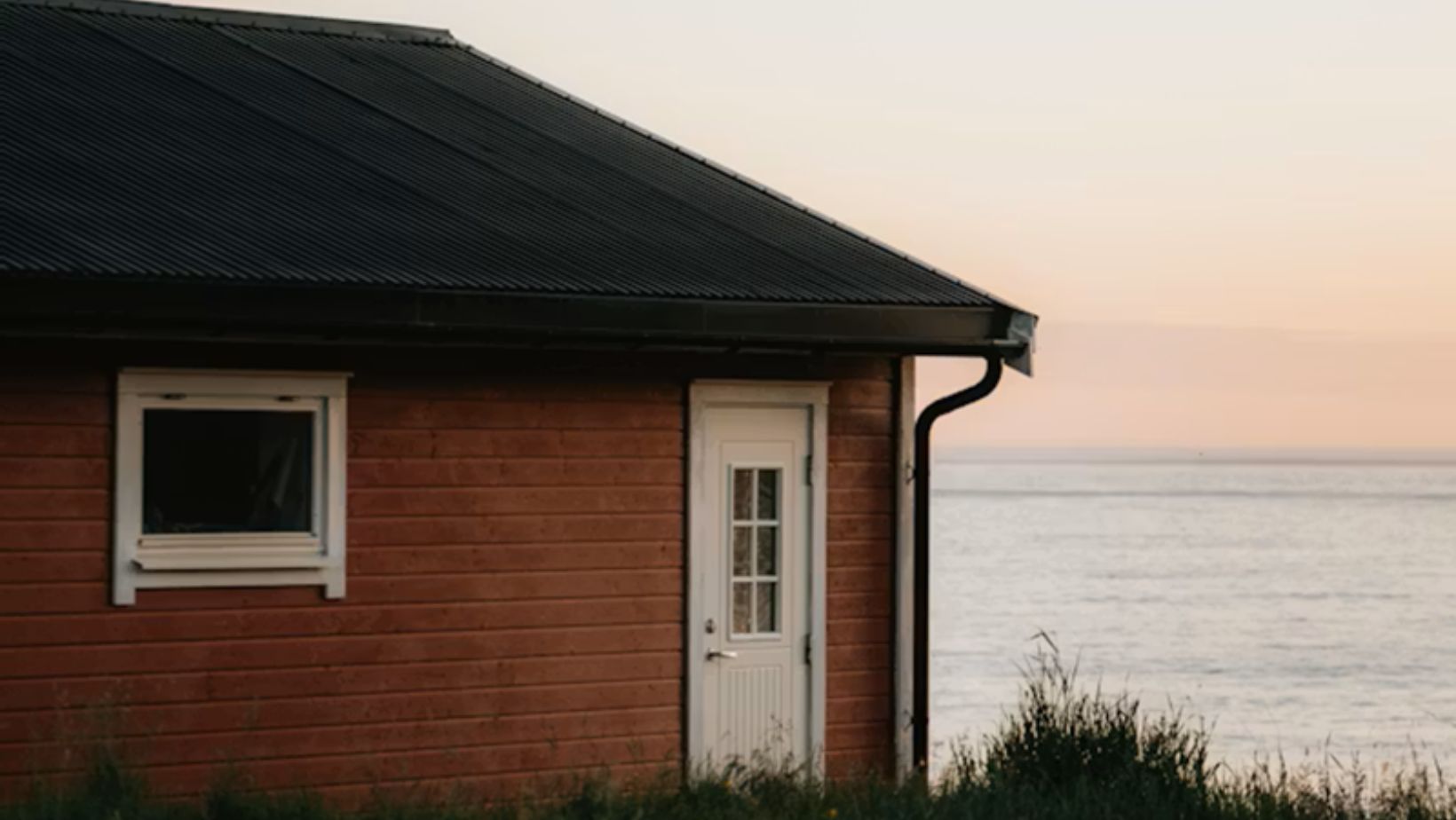 Red house by the ocean at sunset