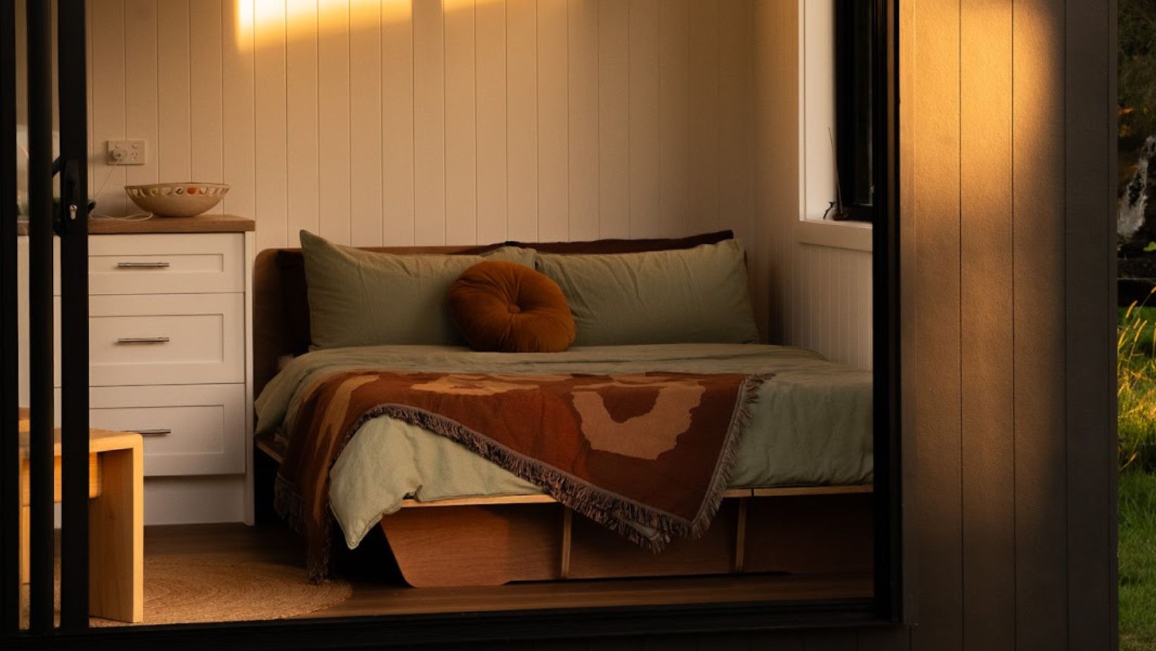 Sunlight warms a minimalist cabin’s interior through an open sliding door