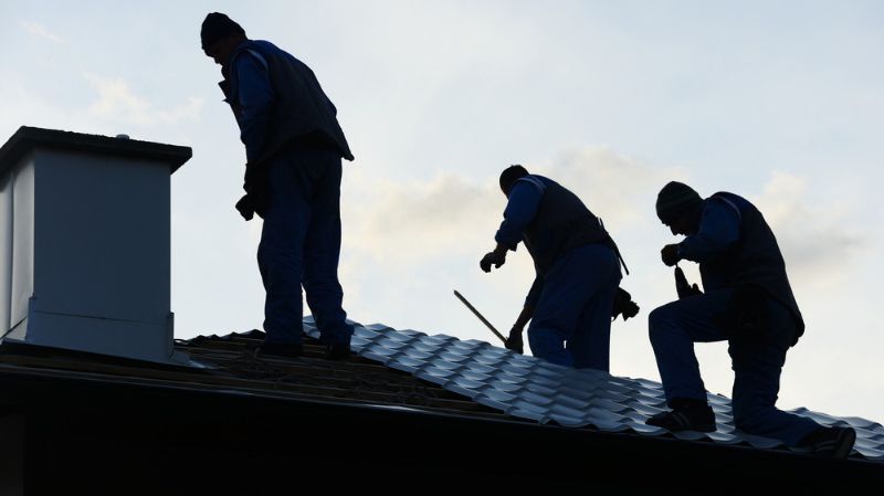 Three men fixing the roof