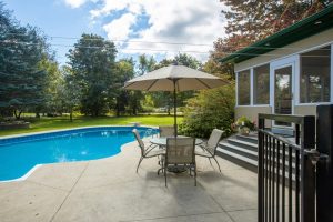a patio with a table and chairs next to a pool