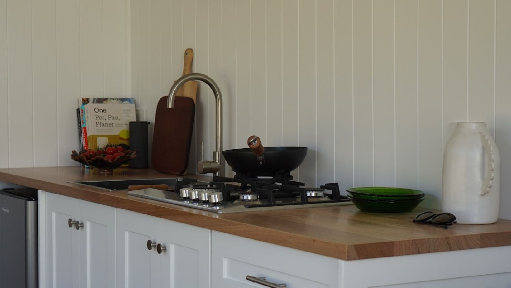 modern kitchenette with white cabinets and a wooden countertop