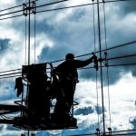 A silhouette of a worker in a lift is positioned against a large glass facade