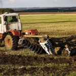 The tractor plows and harrows the land in a large field