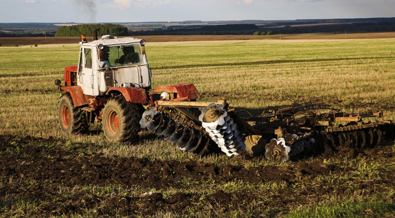 The tractor plows and harrows the land in a large field