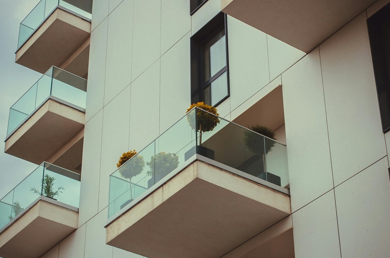 A modern apartment building’s glass balconies with potted plants A modern apartment building's glass balconies with potted plants