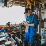 Man in a shed reading the label of varnish