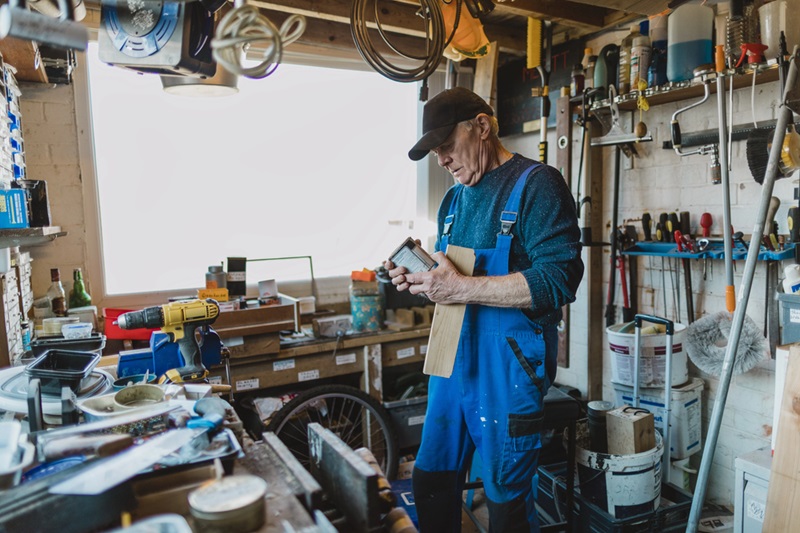Man in a shed reading the label of varnish Man in a shed reading the label of varnish