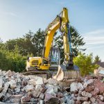 Yellow excavator on top of construction waste