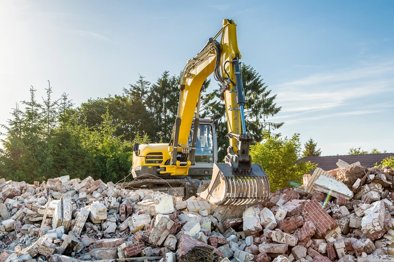 Yellow excavator on top of construction waste