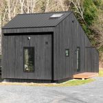 minimalist cabin features a striking black wood exterior with a matte metal roof
