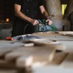 A craftsman skillfully sanding wood on a workbench in a dimly lit workshop