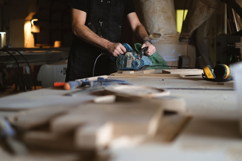 A craftsman skillfully sanding wood on a workbench in a dimly lit workshop