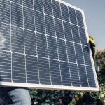 Close-up of technician with safety gear installing a solar panel outdoors