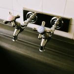 Detailed view of chrome sink faucets with classic hot and cold labels in a kitchen setting