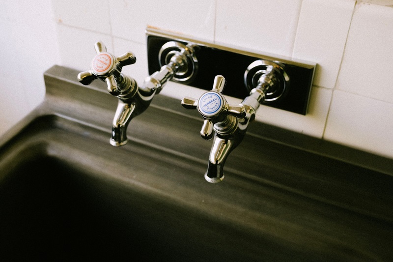 Detailed view of chrome sink faucets with classic hot and cold labels in a kitchen setting Detailed view of chrome sink faucets with classic hot and cold labels in a kitchen setting