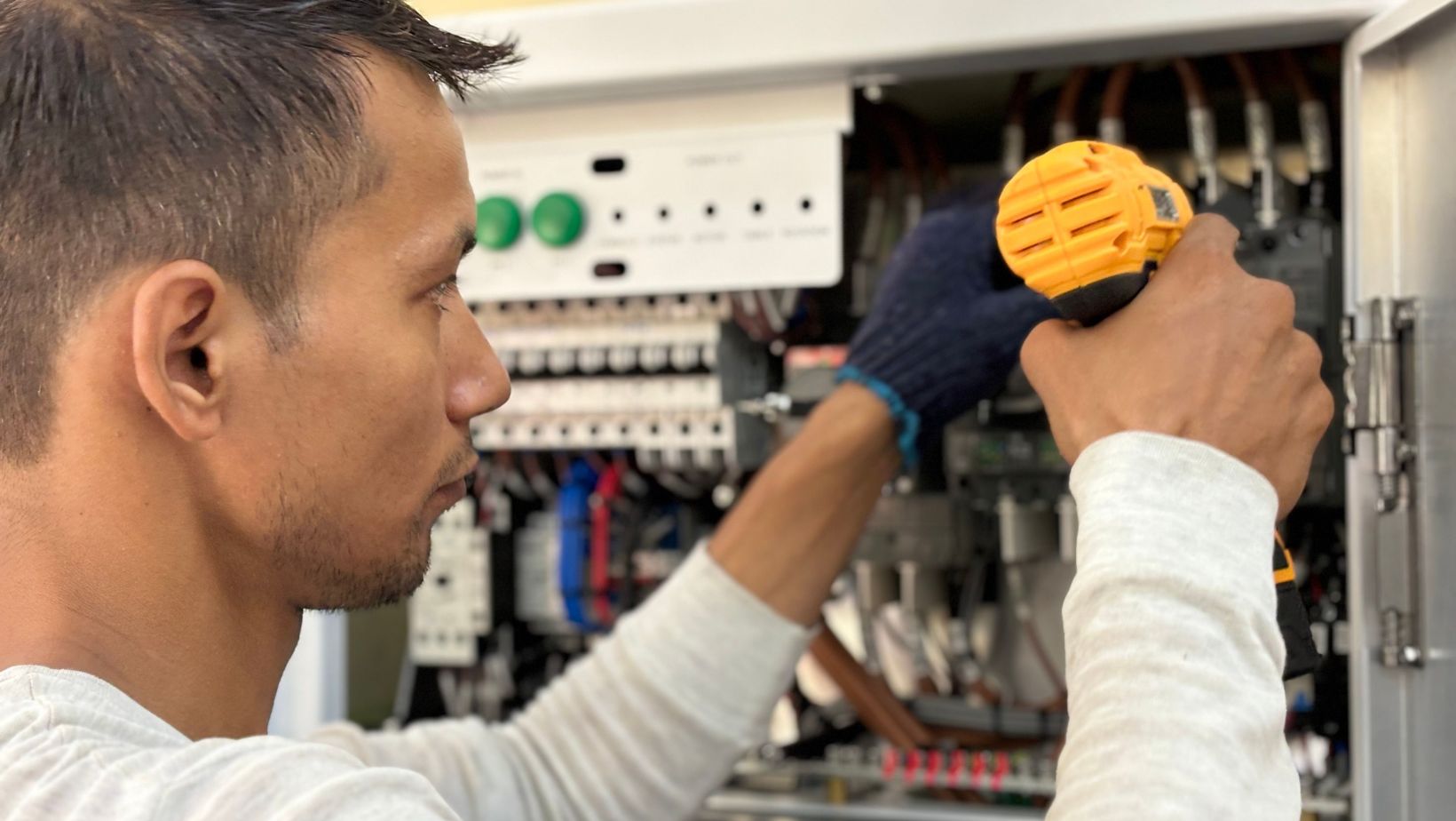 Focused technician using a drill on an electrical panel, showcasing expert workmanship