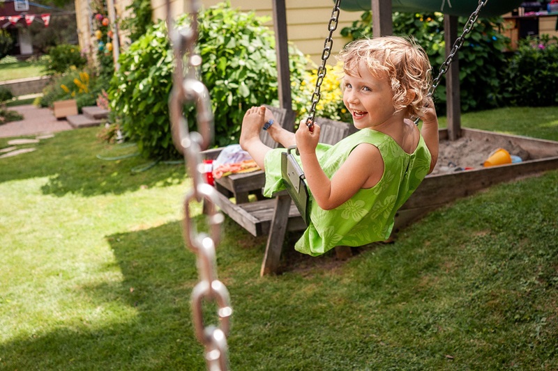 Joyful child swinging in a backyard garden on a sunny day, capturing summer fun