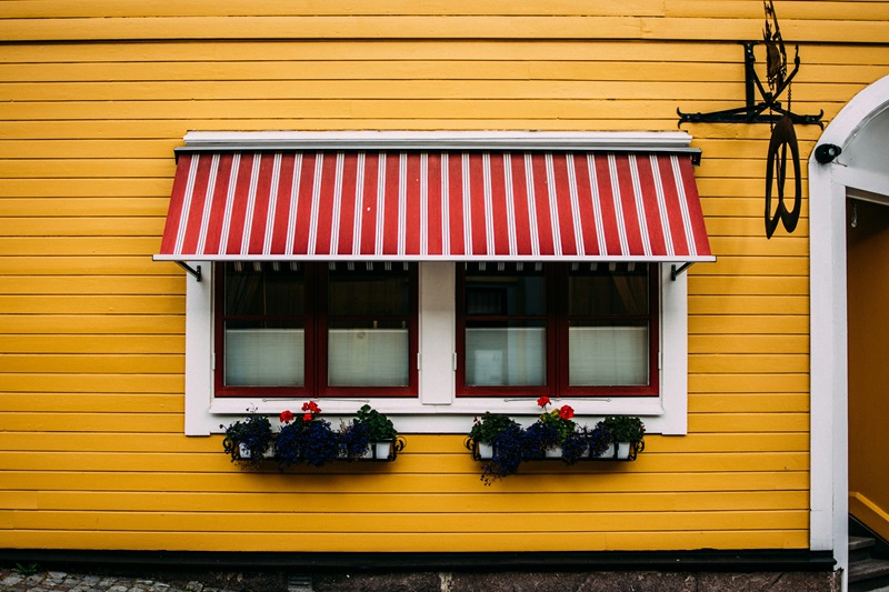Vibrant Yellow Wooden Facade with Red Striped Awning