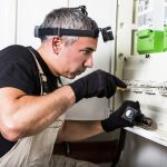 Electrician repairs and measures fuse box or switch box
