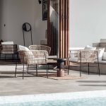 Luxurious outdoor seating area by the pool with modern wicker chairs and soft cushions