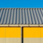 Minimalist Industrial Architecture with Corrugated Metal Roof and Yellow Accent Wall