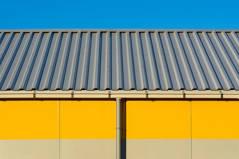 Minimalist Industrial Architecture with Corrugated Metal Roof and Yellow Accent Wall Minimalist Industrial Architecture with Corrugated Metal Roof and Yellow Accent Wall