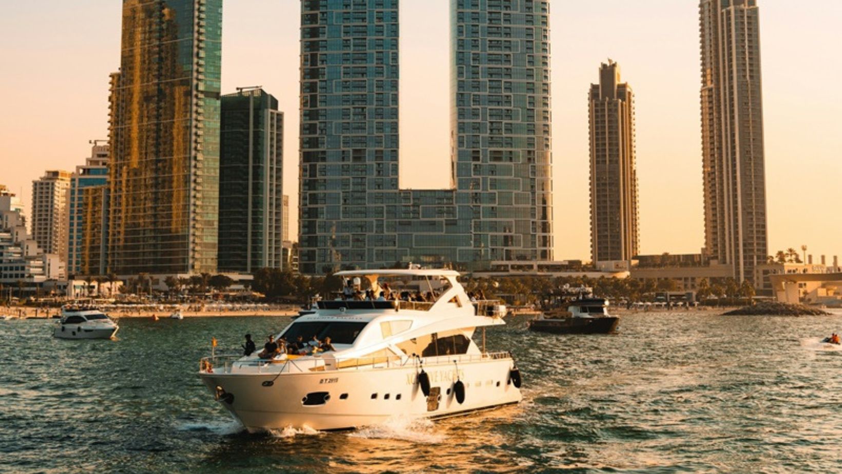 The yacht sailing past modern skyscrapers at sunset