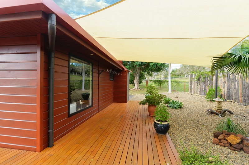Wooden house with deck, shade sail, and gravel garden Wooden house with deck, shade sail, and gravel garden