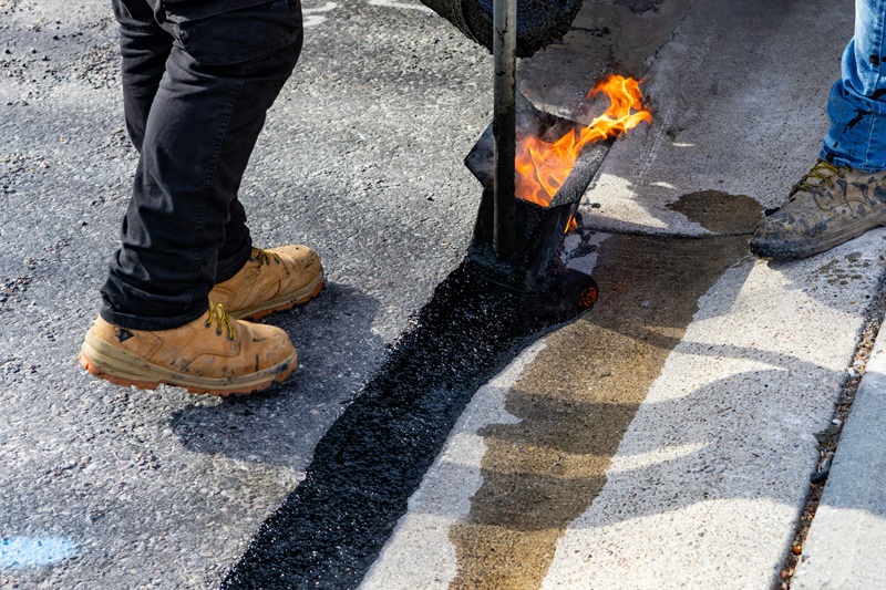 Workers applying hot asphalt with a torch Workers applying hot asphalt with a torch