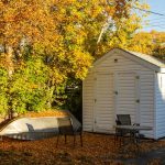 a small white shed with a boat in the yard