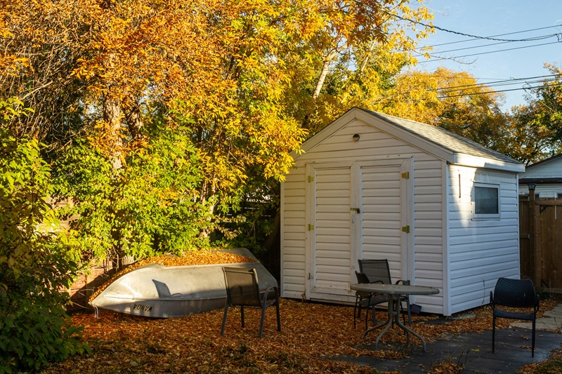 a small white shed with a boat in the yard a small white shed with a boat in the yard