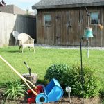 a yard with a lawn mower, garden tools and a birdhouse
