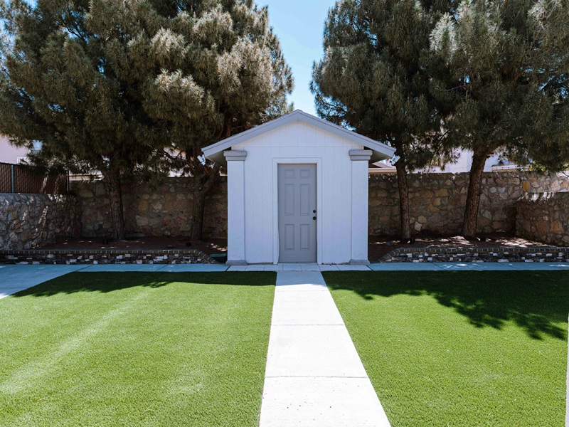 a small white shed sitting in the middle of a yard