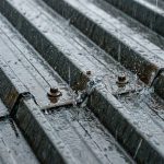 A close-up of a corrugated steel shed roof showing water dripping near a roof