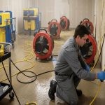 A professional restoration technician assessing a room with a commercial dehumidifier
