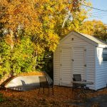 a small white shed with a boat in the yard.